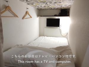 Cafe&Hostel きみといちご في أوساكا: غرفه فيها تلفزيون وسرير