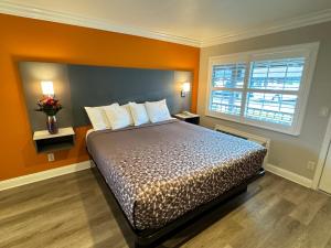 ein Schlafzimmer mit einem Bett mit orangefarbenen Wänden und einem Fenster in der Unterkunft Padre Oaks in Monterey