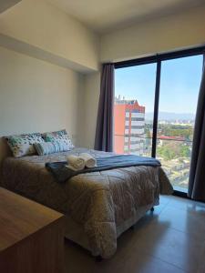 ein Schlafzimmer mit einem Bett und einem großen Fenster in der Unterkunft Apartamento Cerca del Aeropuerto in Guatemala