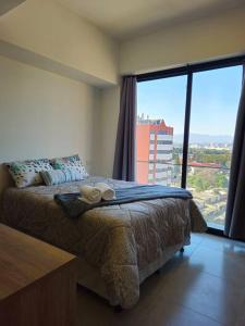 a bedroom with a bed and a large window at Apartamento Cerca del Aeropuerto in Guatemala