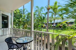 einen Balkon mit einem Tisch, Stühlen und Palmen in der Unterkunft Unit 4 @ Tropical Reef Apartments in Port Douglas