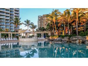 una piscina con palmeras y edificios en 2-Bed with Secure Parking, Pools, Spa, Gym & BBQ, en Gold Coast