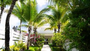 a house with palm trees and a white fence at Boutique Hotel Las Flores Punta Cana in Punta Cana