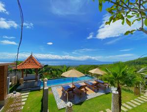 a pool with chairs and umbrellas and the ocean at Mere Sea View Penida in Nusa Penida