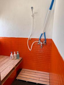 y baño con ducha y azulejos de color naranja. en TOTONOU Place, en Asahikawa