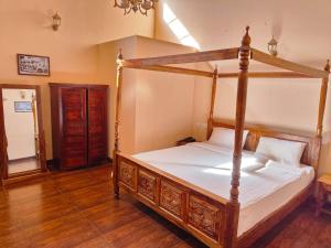 a bedroom with a wooden canopy bed with white sheets at Heritage Inn by Brown Tree Resorts in Ooty