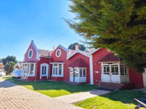 une maison rouge avec des portes blanches sur une cour dans l'établissement Heritage Inn by Brown Tree Resorts, à Ooty