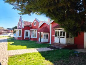 a red house with white doors and a yard at Heritage Inn by Brown Tree Resorts in Ooty