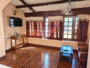 sala de estar con suelo y ventanas de madera y mesa en Heritage Inn by Brown Tree Resorts, en Ooty