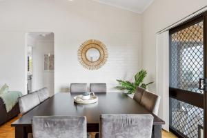 a dining room with a table and chairs and a mirror at Quaint 2-Bed Beach Abode with Ocean Views in Alexandra Headland