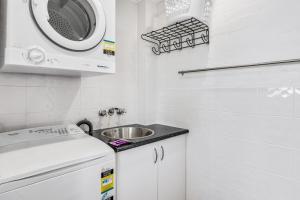 a white kitchen with a sink and a microwave at Quaint 2-Bed Beach Abode with Ocean Views in Alexandra Headland
