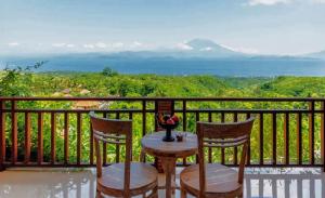 Mere Sea View Resort & Spa في Batununggul: طاولة وكراسي على شرفة مطلة