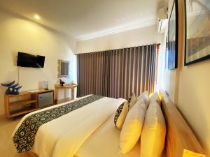 a hotel room with a bed and a television at Mere Sea View Resort & Spa in Batununggul