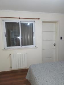 een slaapkamer met een raam, een bed en een deur bij Departamento zona céntrica balcarce in Balcarce