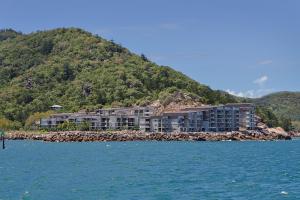 un grand bâtiment sur une île rocheuse dans l'eau dans l'établissement Best at Bright Point Absolute Waterfront Apartment, à Nelly Bay