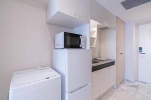 a white kitchen with a microwave on top of a refrigerator at Fujiterrace Yoga in Tokyo