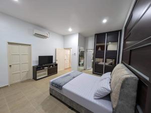 a bedroom with a large bed and a television at D’Garden Cottage with big field in Kluang
