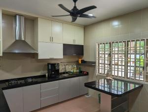 a kitchen with white cabinets and a ceiling fan at D’Garden Cottage with big field in Kluang