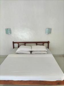 uma cama com lençóis brancos e almofadas num quarto em Nirwana Sea Side Cottages em Lovina