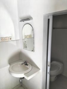 a white bathroom with a sink and a toilet at Nirwana Sea Side Cottages in Lovina