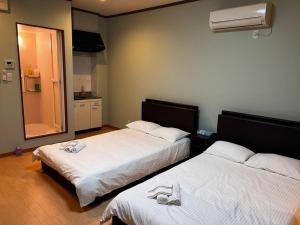 2 camas con zapatillas en una habitación en 全新上线花跡民宿5号館102 独享空间 难波，日本桥4分钟车程！天王寺，通天阁步行圈！, en Osaka