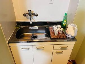 encimera de cocina con fregadero, tazas y tabla de cortar en 全新上线花跡民宿5号館102 独享空间 难波，日本桥4分钟车程！天王寺，通天阁步行圈！, en Osaka