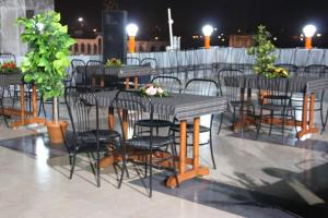 a group of tables and chairs on a patio at night at OYO Home Hotel Skyland in Ahmedabad