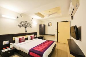 a bedroom with a bed with a tree on the wall at OYO Home Hotel Skyland in Ahmedabad
