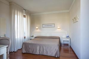 um quarto com uma cama e duas mesas e uma janela em Grand Hotel Bonanno em Pisa