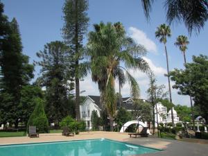a swimming pool in front of a house with palm trees at Luxury Hotel in Bela Bela chateau in Bela-Bela