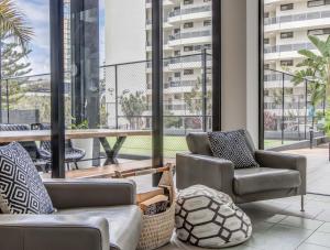 sala de estar con 2 sillas y ventana grande en Neptune Resort, en Gold Coast