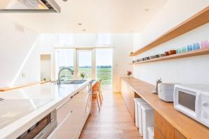 a kitchen with white counters and a large window at One house Naganuma MAOI in Naganuma