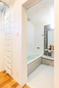 Baño blanco con bañera y espejo en One house Naganuma MAOI en Naganuma