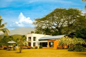 una casa con césped y árboles y montañas al fondo en Villas Mamilú, entrada y salida 100 por ciento flexible en Santa Fe de Antioquia