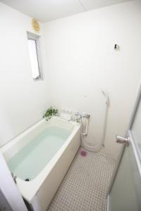 a white bathroom with a tub and a shower at 高原マンション 201 in Horinouchichō