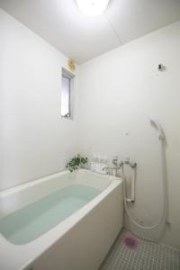 a white bath tub in a bathroom with a window at 高原マンション 201 in Horinouchichō