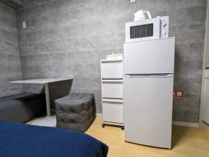 a white refrigerator with a microwave on top of it at Home cruise西小山 in Tokyo