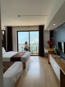 a hotel room with two beds and a balcony with a woman at Roxana Sapa Hotel - by Bay Luxury in Sapa +8 photos