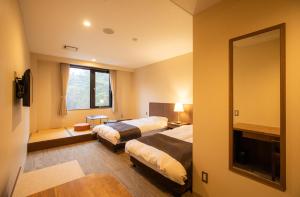 富士河口湖町にある本栖フェニックスホテルのベッド2台と鏡が備わるホテルルームです。