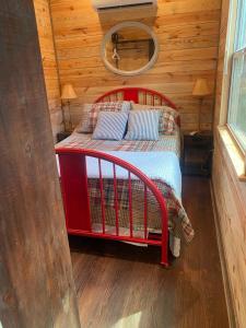 a bedroom with a red bed in a log cabin at Tiny House Oasis: Nature Escape in Nacogdoches