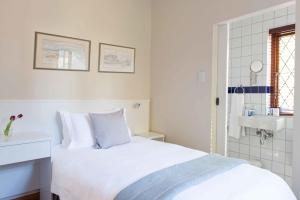 
a white bed sitting in a bedroom next to a window at Knightsbury Guest House in Cape Town

