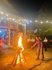 un hombre está encendiendo un fuego en un trípode en Eco Homestay Mai Chau - Venuestay, en Mai Chau