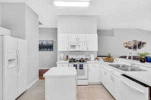 uma cozinha branca com electrodomésticos brancos e armários brancos em Happy place! 2 king beds, hot tub, free parking em Riverview
