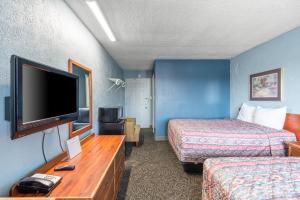 a hotel room with two beds and a flat screen tv at Broadway Inn in Council Bluffs