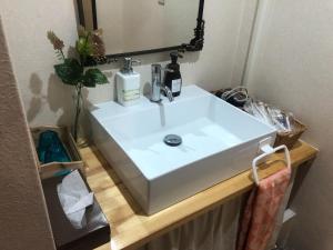 lavabo blanco en el baño con espejo en おやど紀伊国屋新地町 en Nagasaki