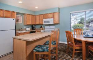 a kitchen with wooden cabinets and a table and a refrigerator at WorldMark Birch Bay in Birch Bay