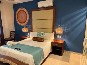 a bedroom with a bed with a blue wall at Suites Valentina in Puerto Morelos