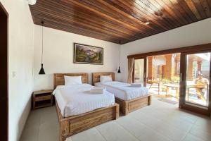 a bedroom with two beds and a balcony at Pondok DD Canggu in Canggu