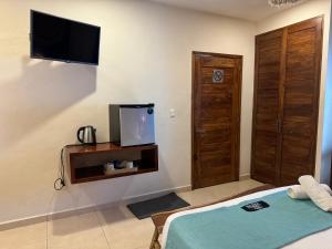a bedroom with a bed and a tv on the wall at Suites Valentina in Puerto Morelos
