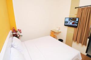 Ruma Ruma Hotel Kenten - Palembang في Sukarami: غرفة فندق بسرير وتلفزيون